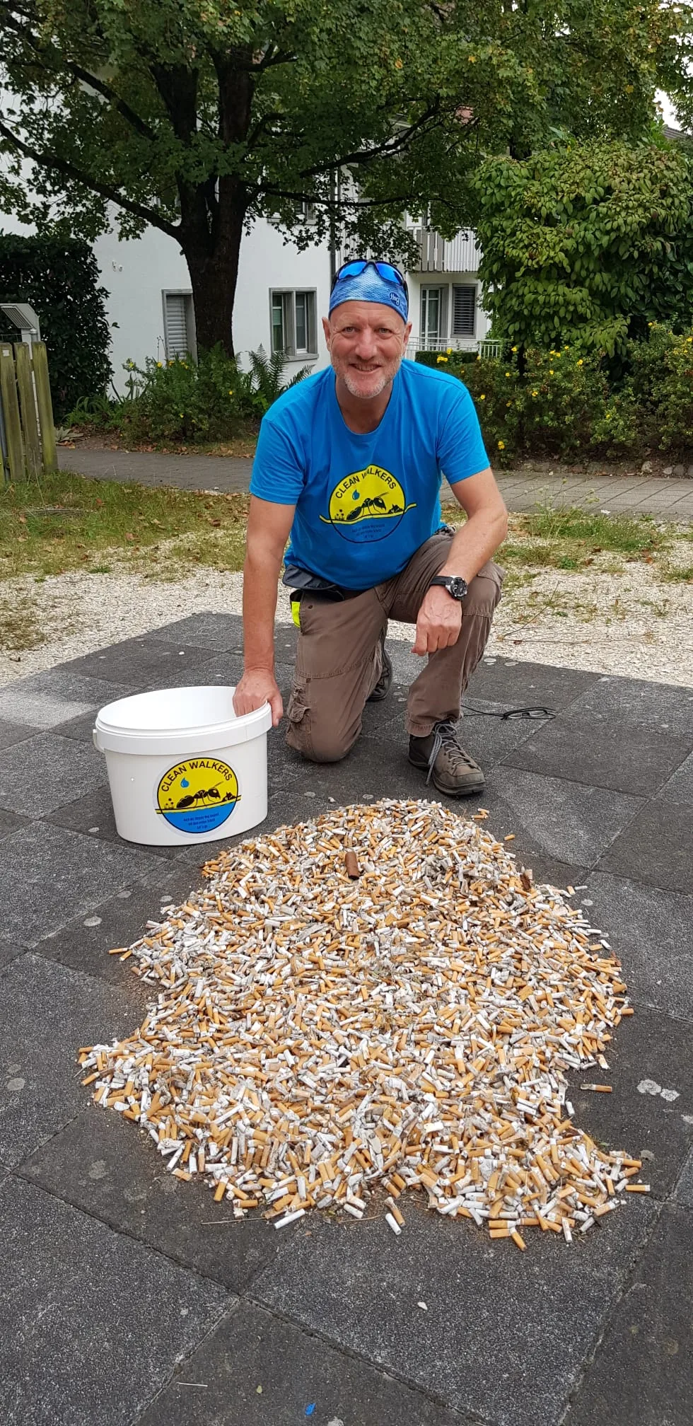 Ein Mann vor einem grossen Haufen Zigarettenstummeln. 